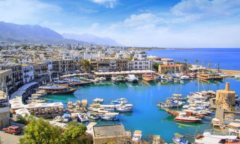 Kyrenia Harbour in Northern Cyprus with colorful boats, historic buildings, and scenic mountain backdrop under blue skies – Summer 2025